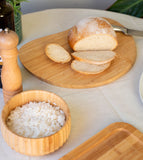 tábua irregular de bambu decorando uma mesa posta com pão e outros alimentos 